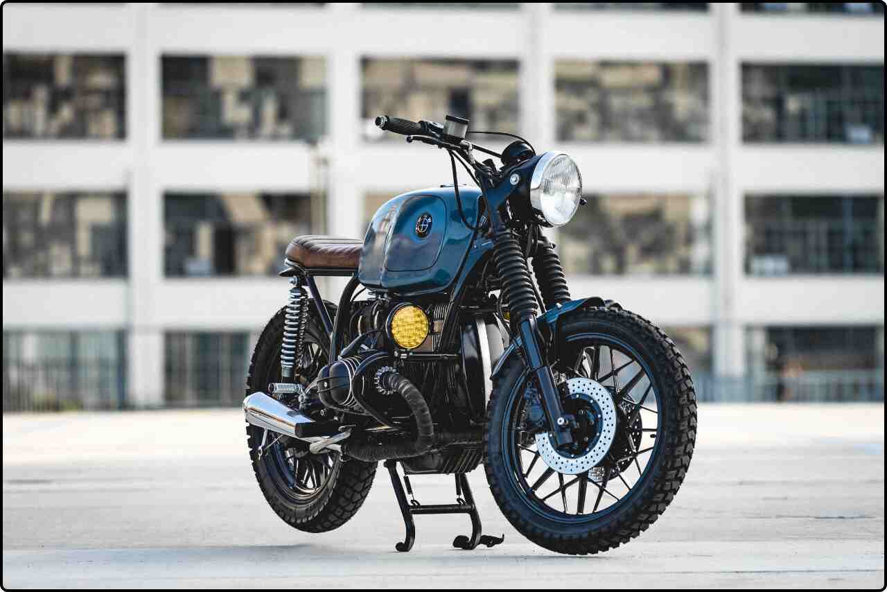 Black-blue motorcycle parked on a city street with buildings in the background.